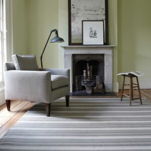 Isis Reed Flatweave Rug in living room with fireplace and armchair
